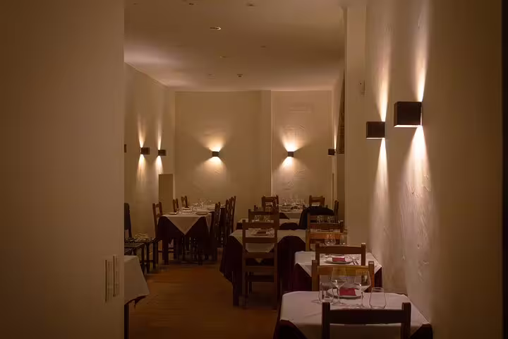 Cozy Lisbon restaurant setting with dim lighting and neatly arranged tables for a Fado dinner experience.