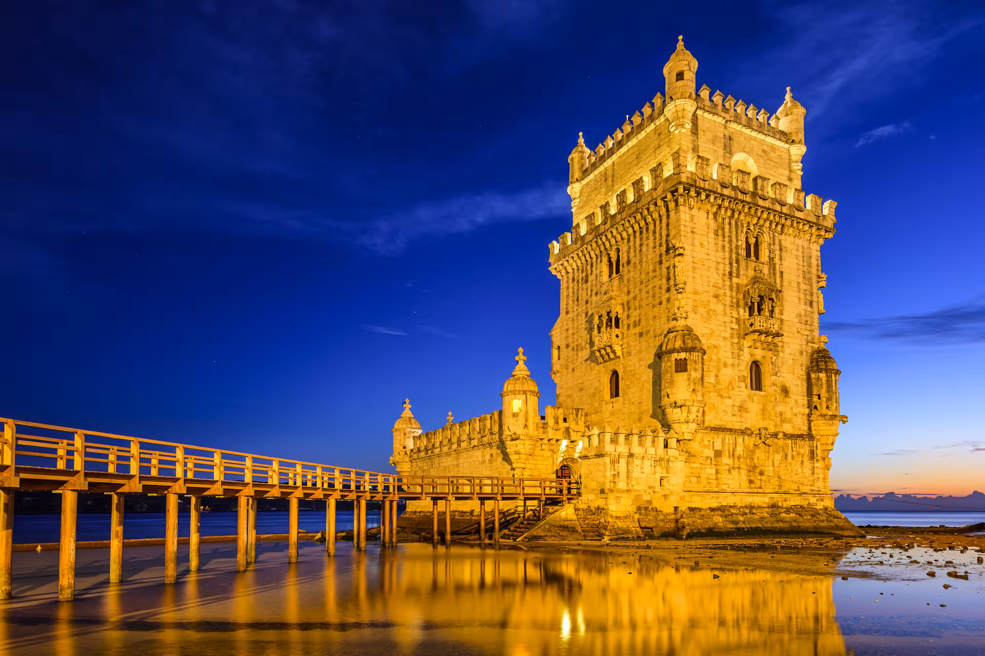 Belem Tower lit up at twilight, showcasing Lisbon's historic charm on the Fado Night Tour with Dinner.