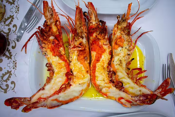 Grilled prawns served with garlic butter on a white plate, part of the Discover Lisbon full-day private tour and gastro experience.