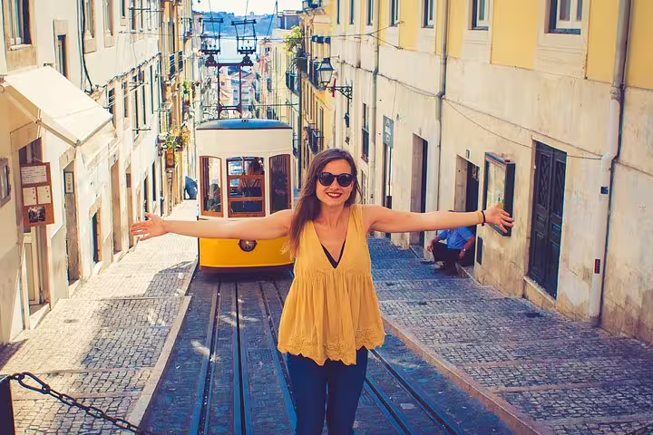 Woman joyfully posing in front of iconic Lisbon tram on a cobblestone street during a private tour of Lisbon highlights.