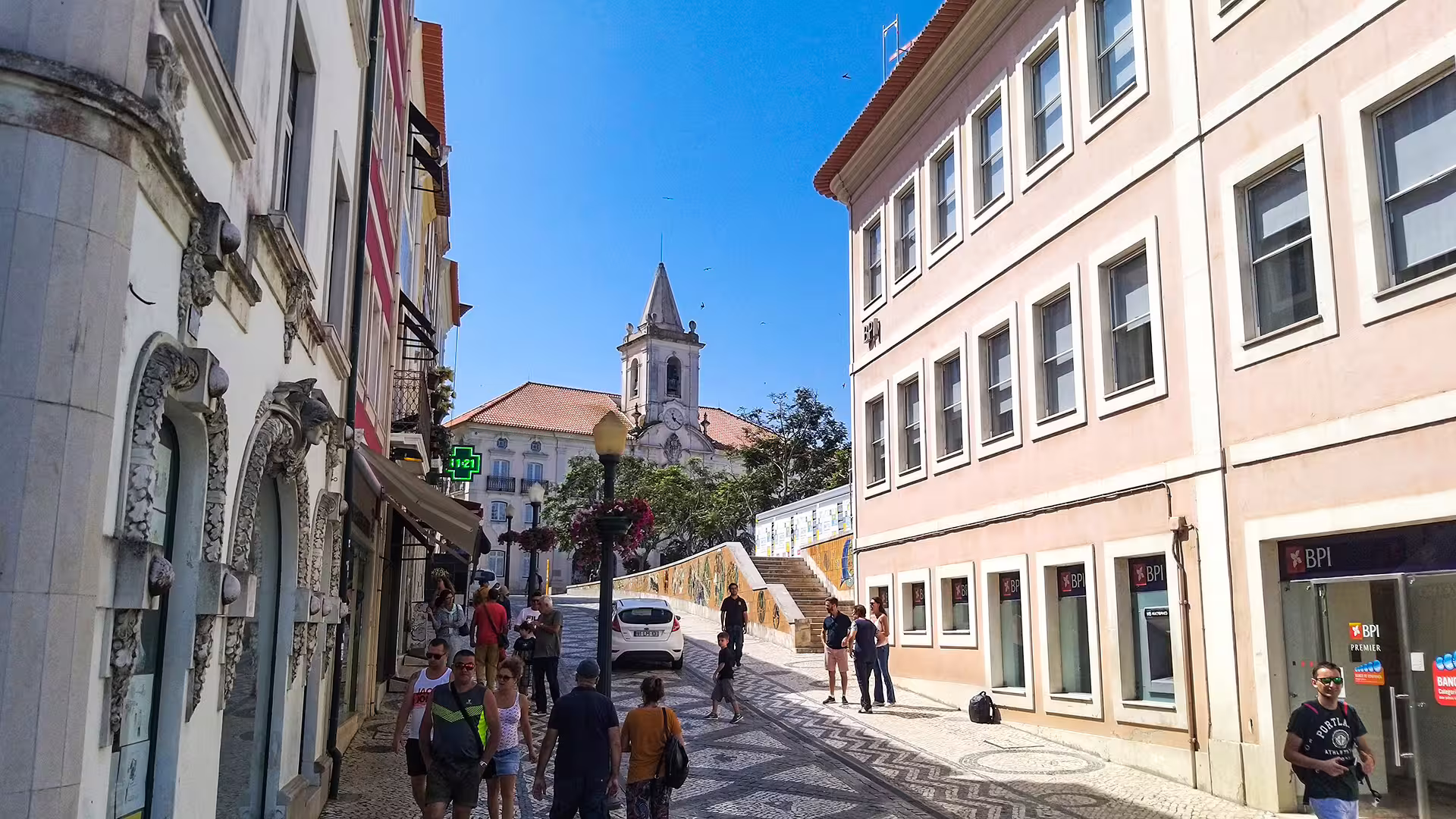 Scenic street view in Lisbon with historic architecture, bustling pedestrians, and a church, perfect for a private tour to Porto.
