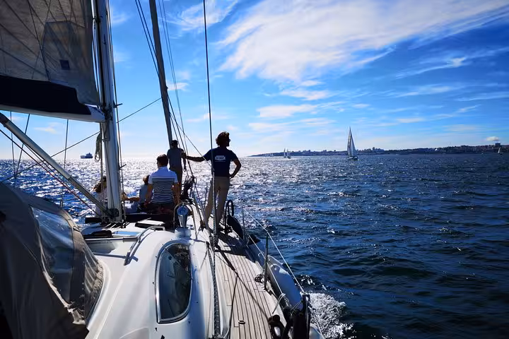 Guests relaxing on luxury sailing yacht deck in Lisbon, Tagus River cruise with 2 drinks and ocean views