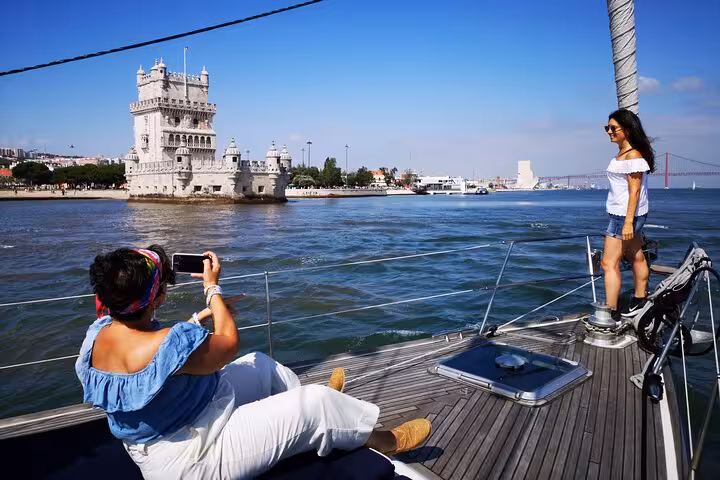 Guests on luxury sailing yacht by Belém Tower in Lisbon on the Tagus River, enjoying a tour with 2 drinks