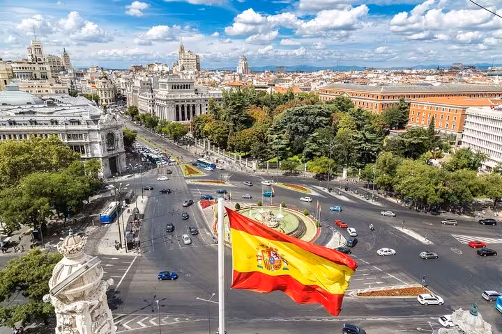 Panoramic view of Madrid's bustling streets with the Spanish flag, highlighting the Madrid destination on the luxury transfer.