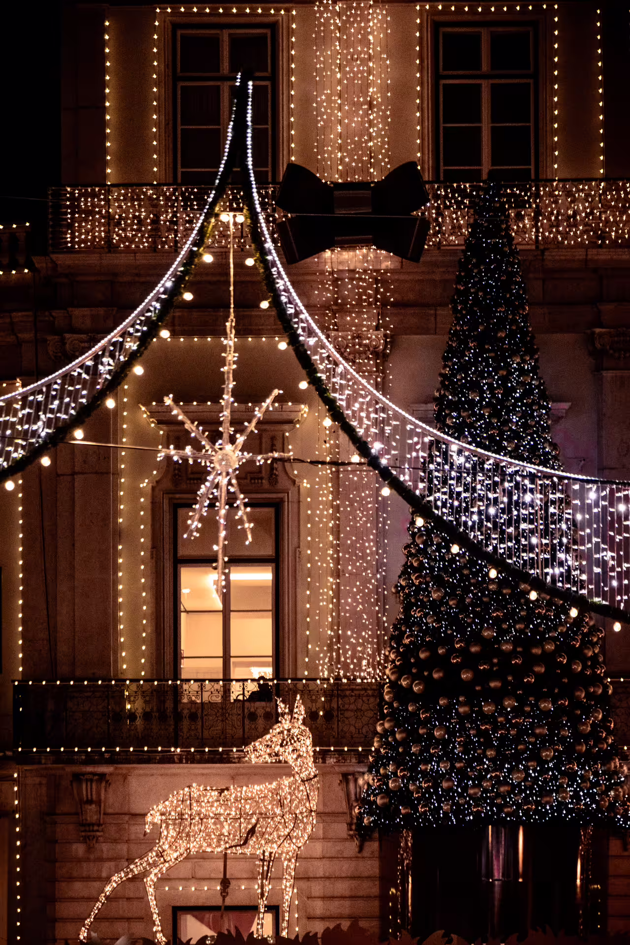 Lisbon's enchanting Christmas lights illuminate a festive street with a decorated tree and reindeer during a private night photo walk.