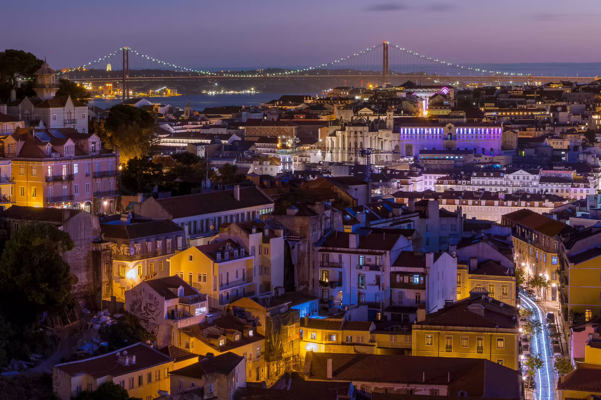 Lisbon skyline illuminated at night with festive Christmas lights, featuring the iconic bridge in a magical holiday atmosphere.