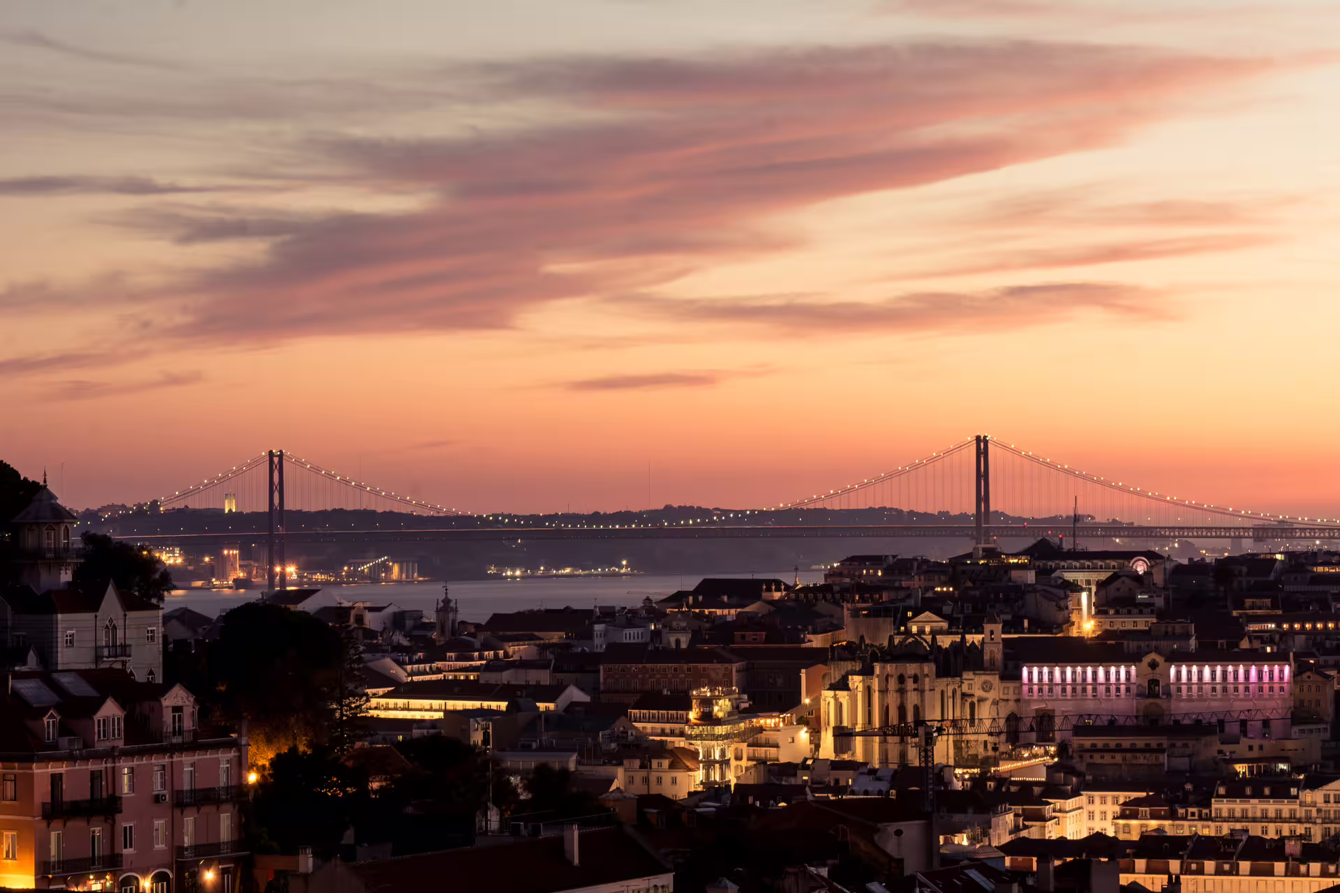Sunset view of Lisbon with illuminated cityscape and bridge, perfect for a private night photo walk capturing iconic sights.
