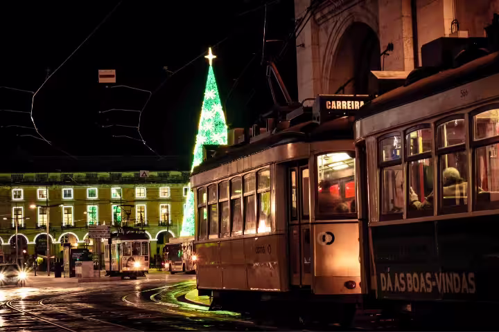 Lisbon's vintage tram passes by a glowing Christmas tree and illuminated square during a festive night photo walk tour.