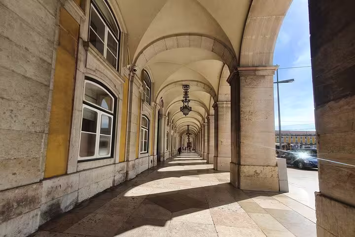 Historic Lisbon arcade with sunlight casting shadows, showcasing classic architecture on the Old Town, New Town & Belem tour.