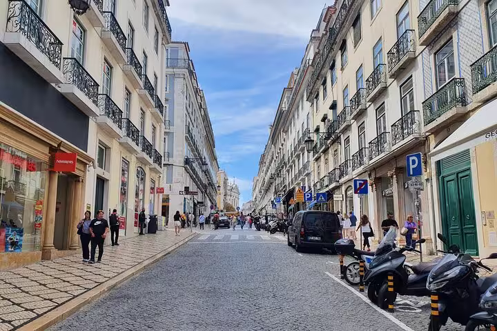 Charming Lisbon street scene showcasing traditional architecture, bustling pedestrians, and vibrant city life on a sunny day.