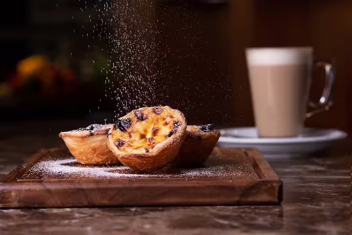 Delicious pastel de nata dusted with sugar, served with coffee, highlighting Lisbon's culinary delights on a private half-day tour.