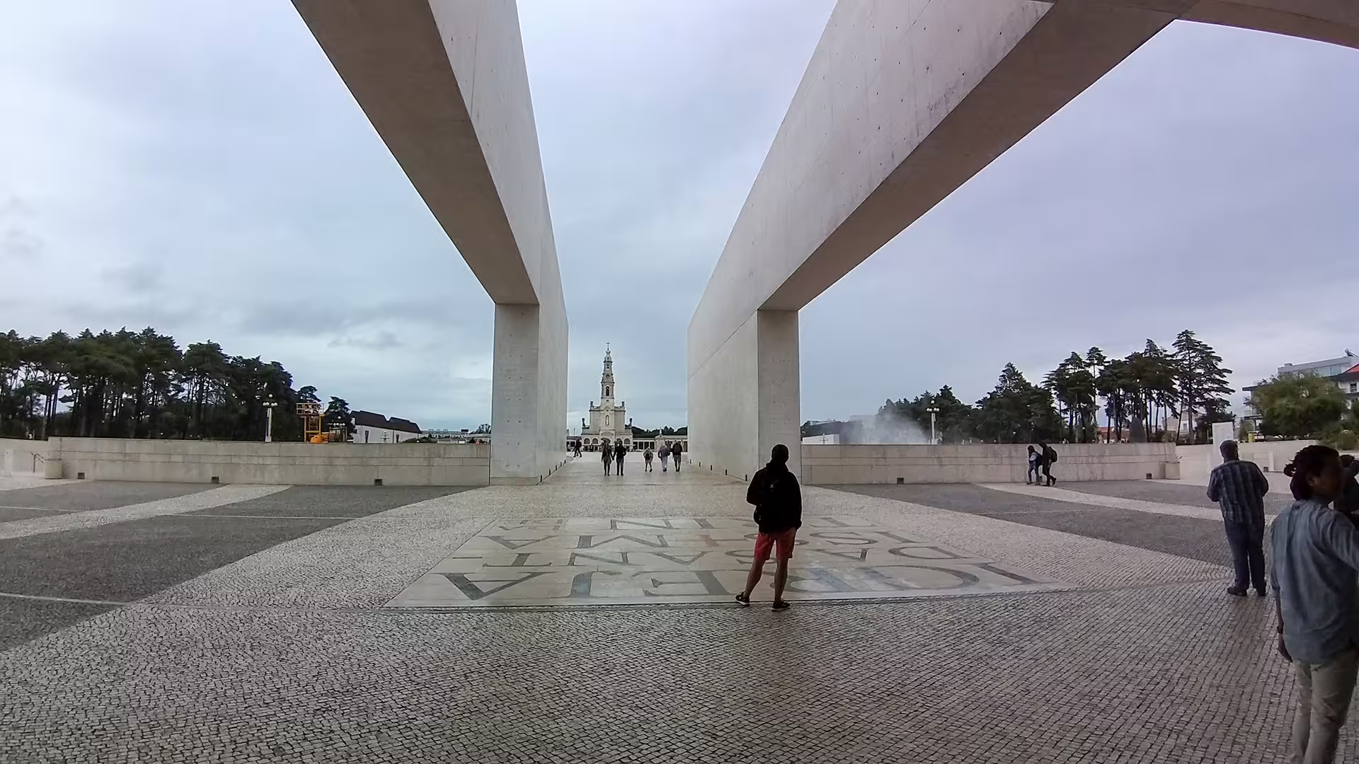 Modern architecture frames a distant church under a cloudy sky, capturing a moment from the Lisbon to Porto private tour adventure.