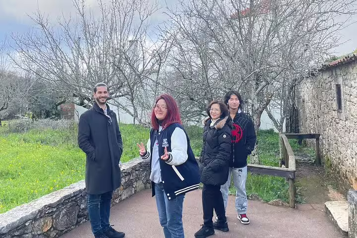 Group enjoying scenic stopover on private Lisbon to Porto transfer, surrounded by lush greenery and rustic architecture.