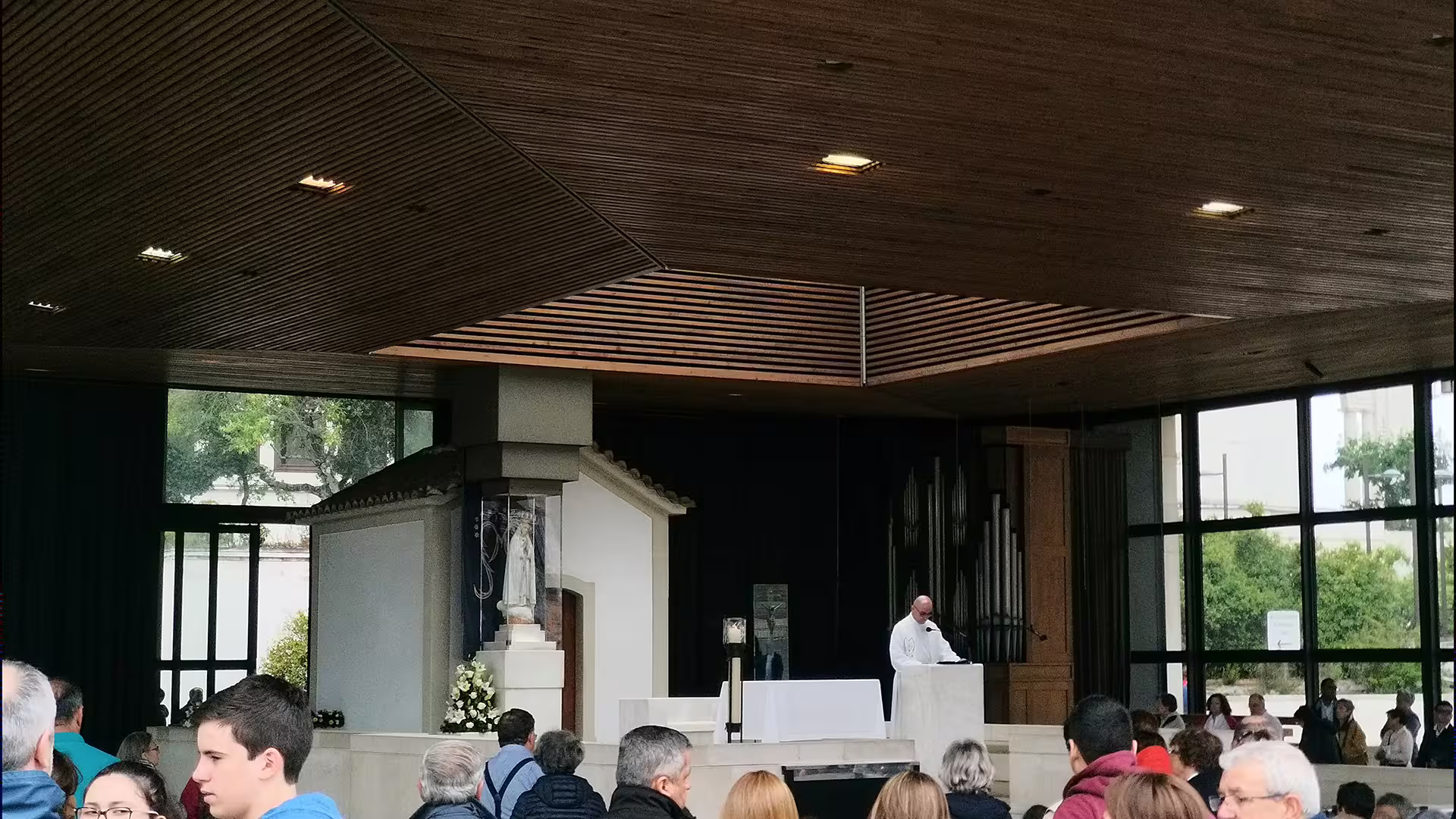 Interior view of a chapel with a priest and gathering of people, showcasing a cultural stop on the Lisbon to Porto tour.