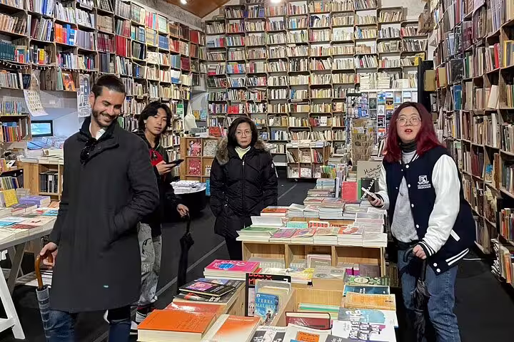 Visitors explore a cozy bookstore filled with colorful books, a cultural stop on the Lisbon to Porto private transfer route.