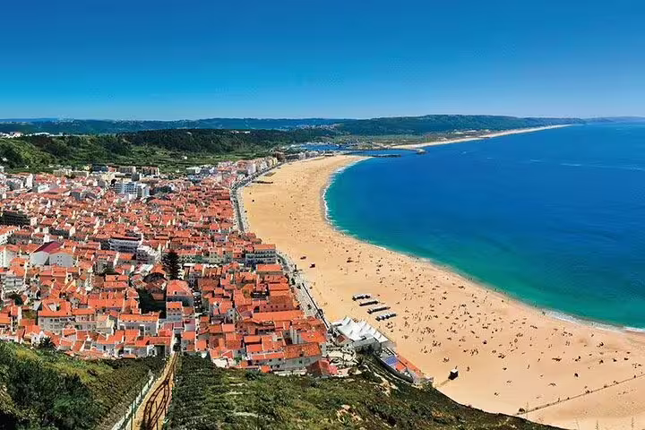 Scenic coastal view of Nazaré beach, a potential stop on the Lisbon to Porto private journey, featuring golden sands and vibrant town.