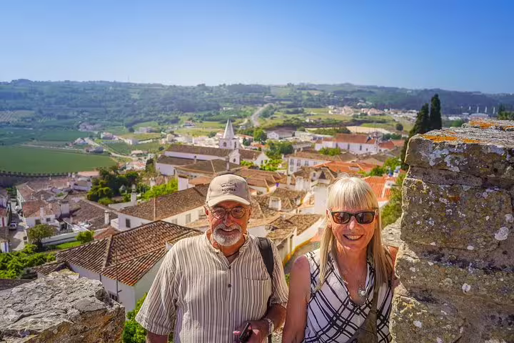 Couple enjoying scenic view of Obidos village during Lisbon to Porto transfer tour with stops in Nazare and Alcobaca.