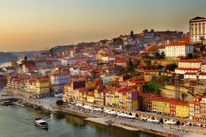 Scenic view of Porto's colorful riverside buildings at sunset, showcasing a vibrant stop on the Lisbon to Porto private transfer tour.