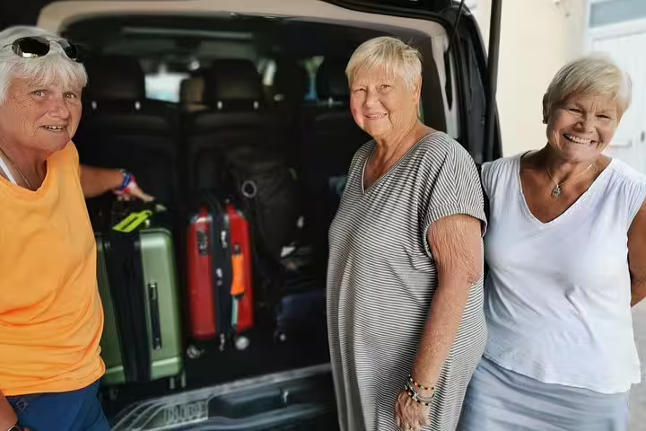 Three people standing by a vehicle with luggage, ready for a Lisbon to Porto transfer with stops in Obidos, Nazare, Alcobaca.