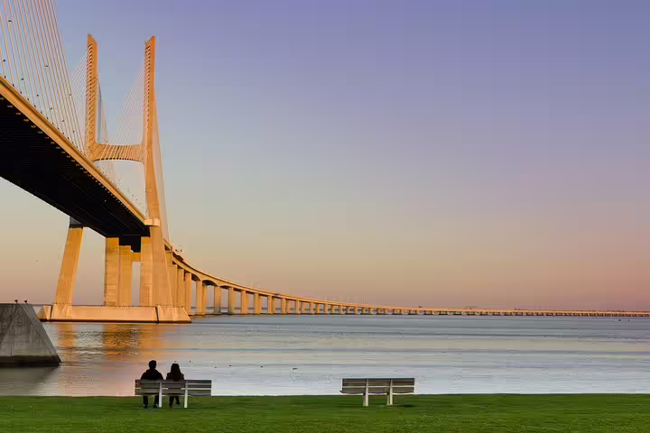 Couple enjoying sunset by the iconic Vasco da Gama Bridge during a Lisbon full-day private tour with custom stops.