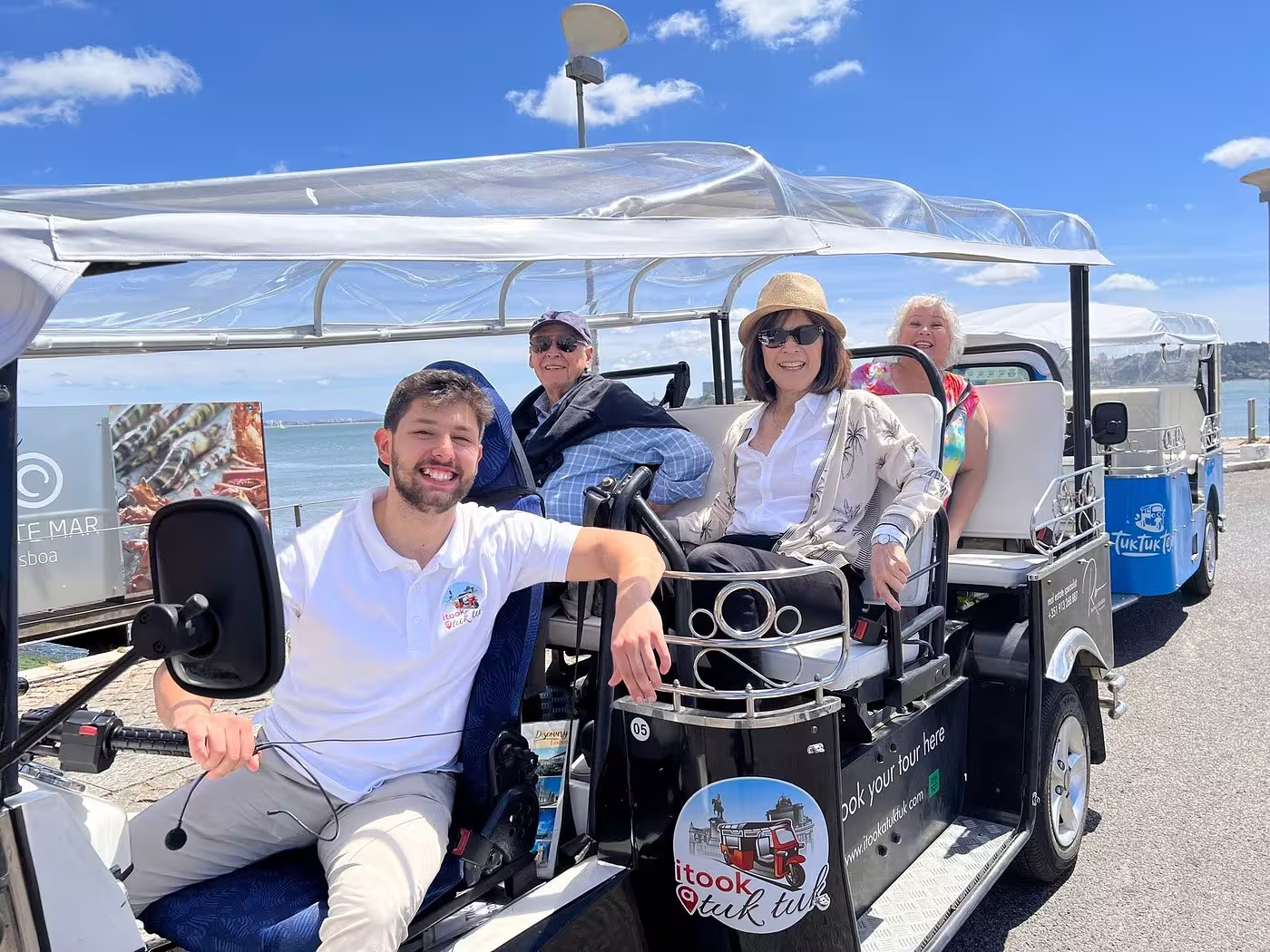 Smiling group enjoying a scenic Lisbon view from a tuk tuk during a private 4-hour tour with an engaging local guide.