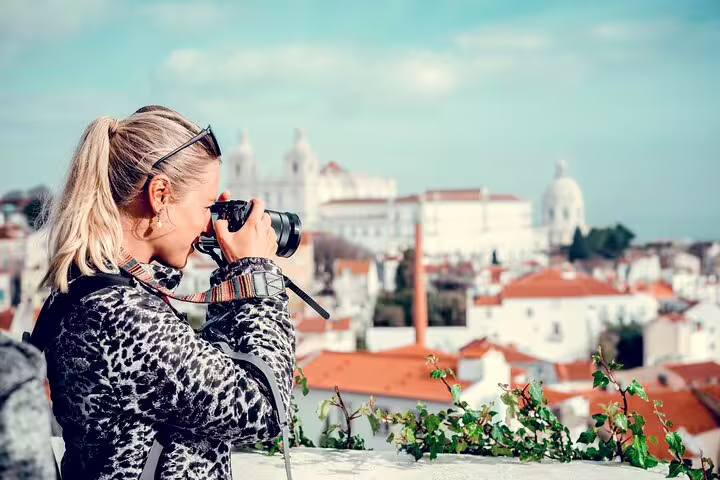 Tourist photographing Lisbon's scenic rooftops and historic architecture during a private walking tour, capturing city highlights.