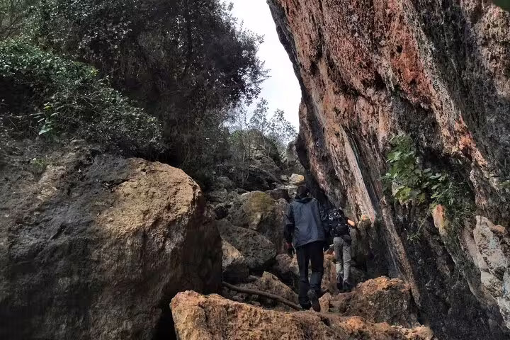 Participants hiking through a narrow gorge with towering rock walls on a full-day climbing adventure from Lisbon.