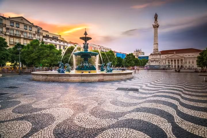 Vibrant Rossio Square in Lisbon featuring a central fountain, intricate cobblestone patterns, and the iconic column at sunset.