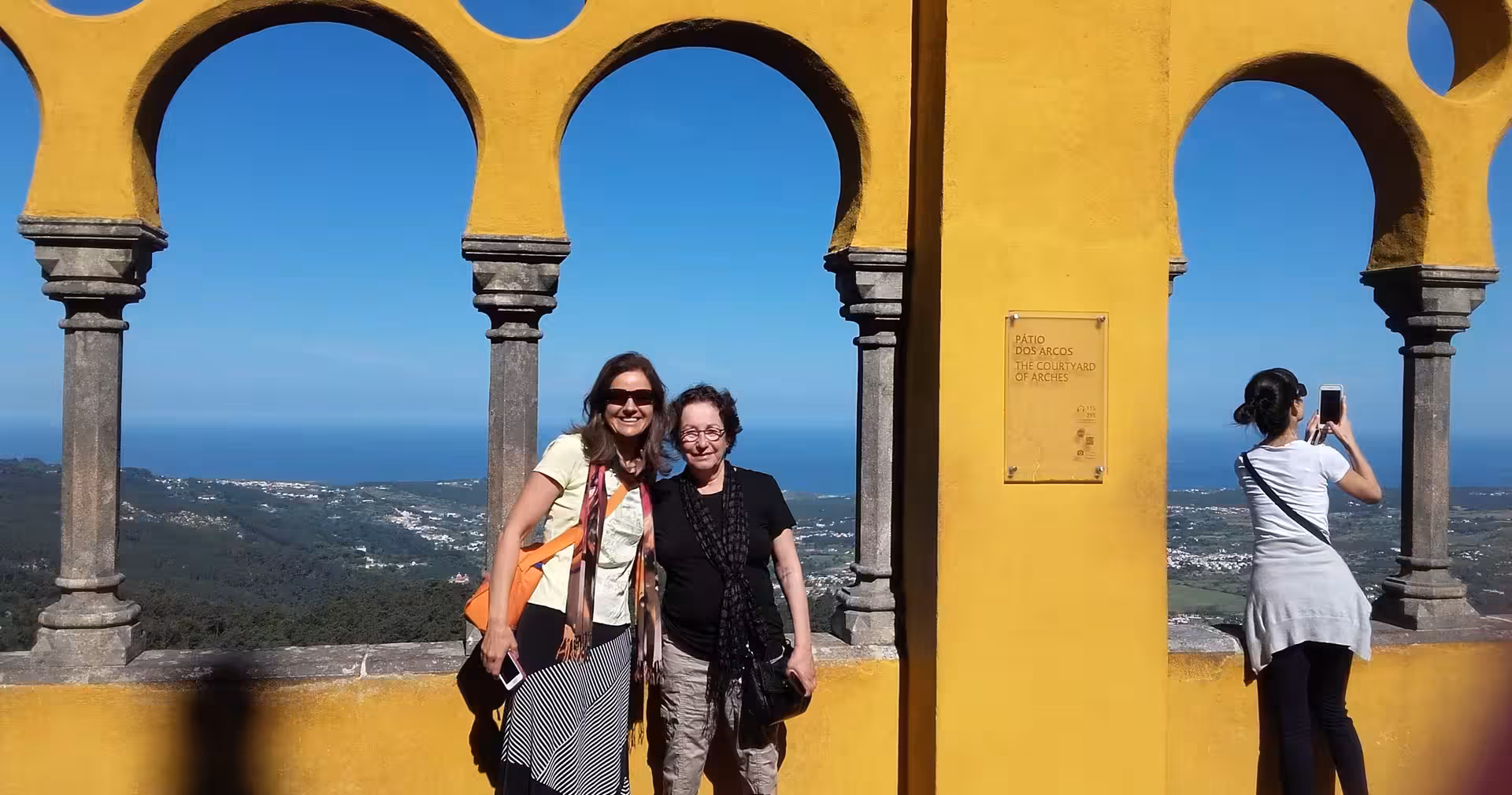 Travelers under Pena Palace arches with panoramic views, stop on Lisbon & Sintra full-day historical highlights tour