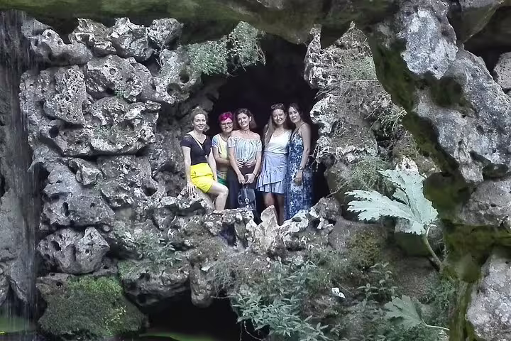 Visitors explore a scenic rock formation in Sintra during a private tour, highlighting Lisbon's nearby natural beauty and culture.
