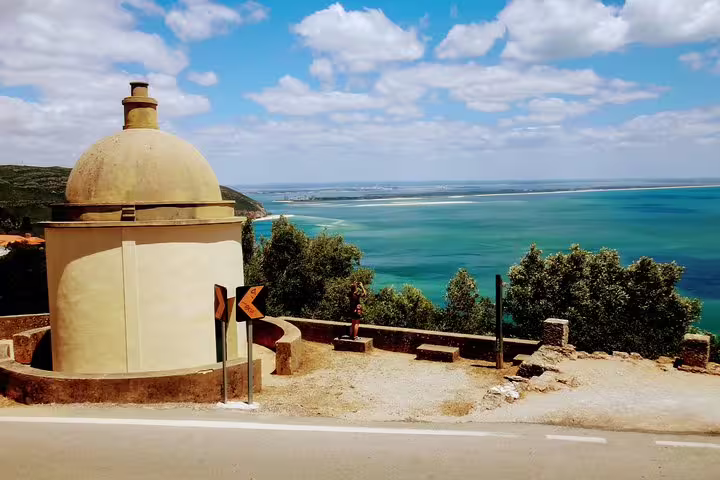 Scenic view of Lisbon's southern coastline with historic architecture and vibrant blue waters, perfect for wine and sights tour.