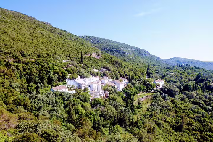 Scenic view of Arrábida mountains and lush greenery surrounding a charming village, featured in Lisbon's South Sights & Wine Tour.