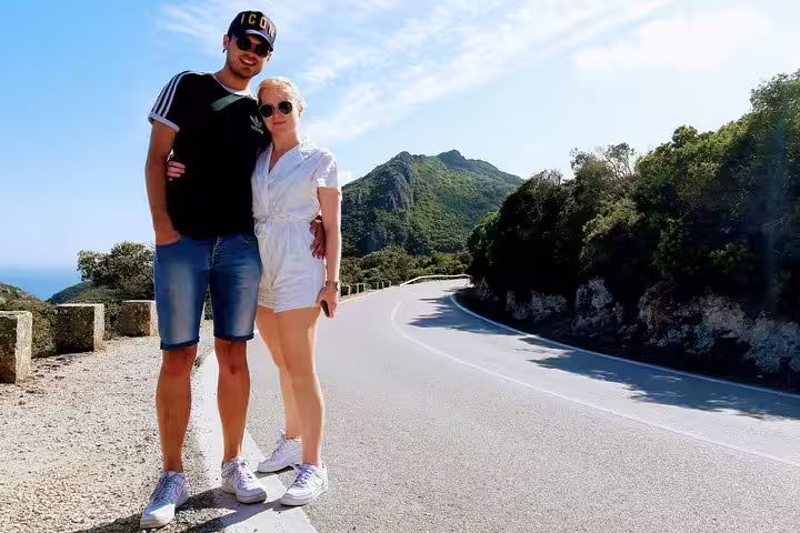 Couple enjoying scenic views on Lisbon's South Sights & Wine Private Tour, with lush hills and winding roads in the background.