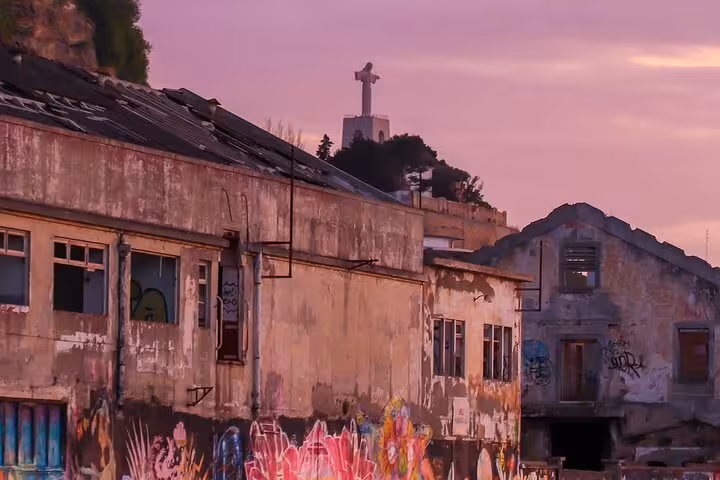 Sunset view of Lisbon's urban street art and Cristo Rei statue, highlighting Portugal's vibrant culture.