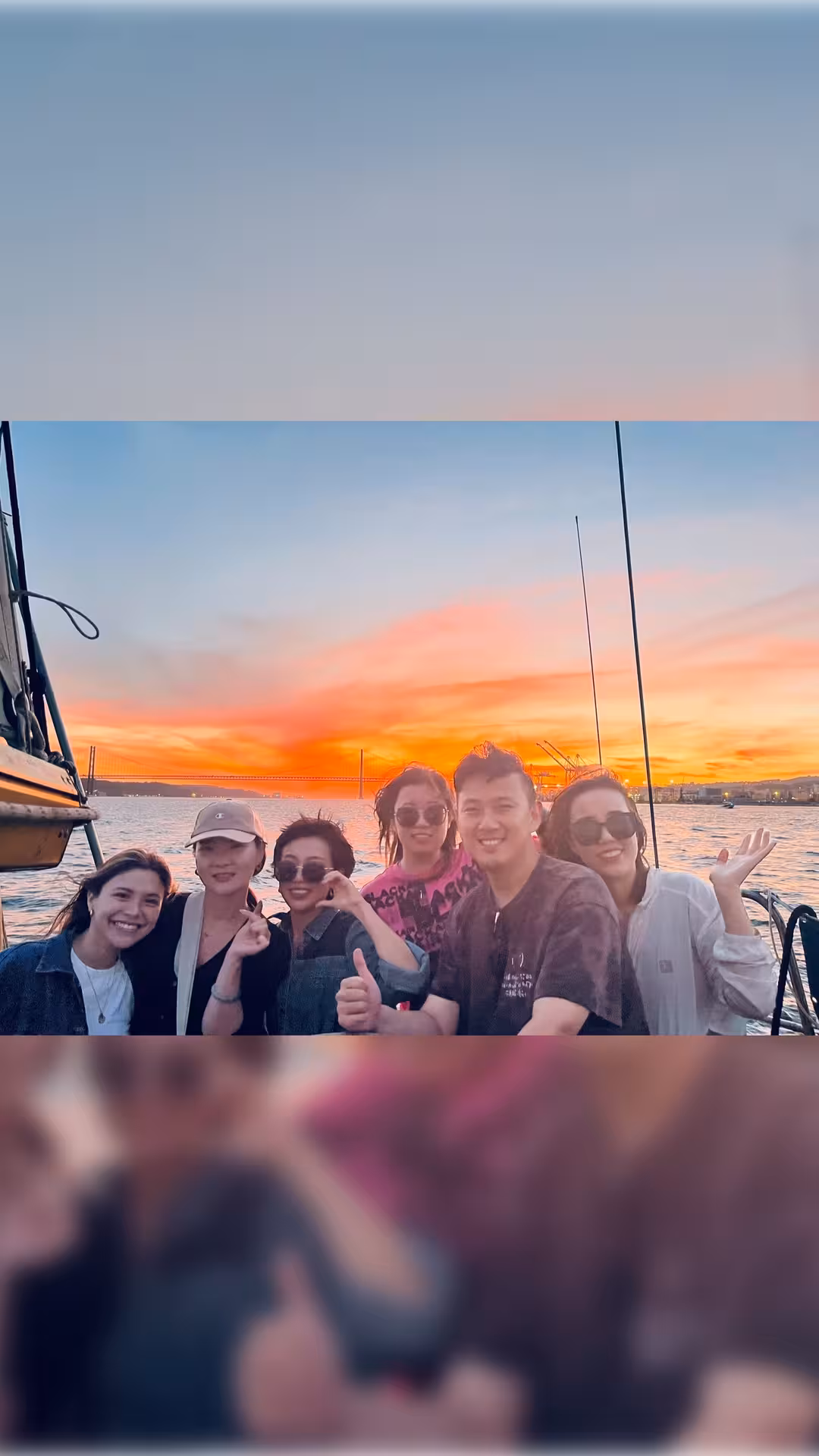 Group selfie on Lisbon sunset boat cruise with welcome drink, Tagus River glowing at dusk by 25 de Abril Bridge