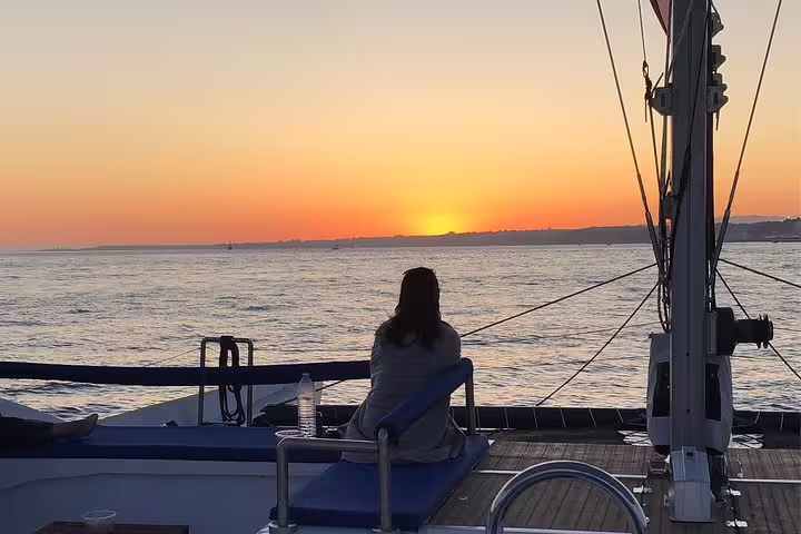 Woman enjoying a serene sunset view over the Tagus River from a catamaran in Lisbon.