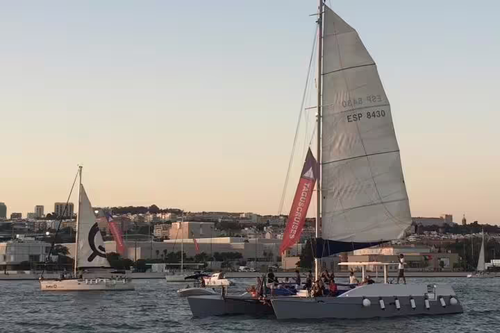 Catamaran sailing on the Tagus River at sunset, offering picturesque views of Lisbon's skyline.