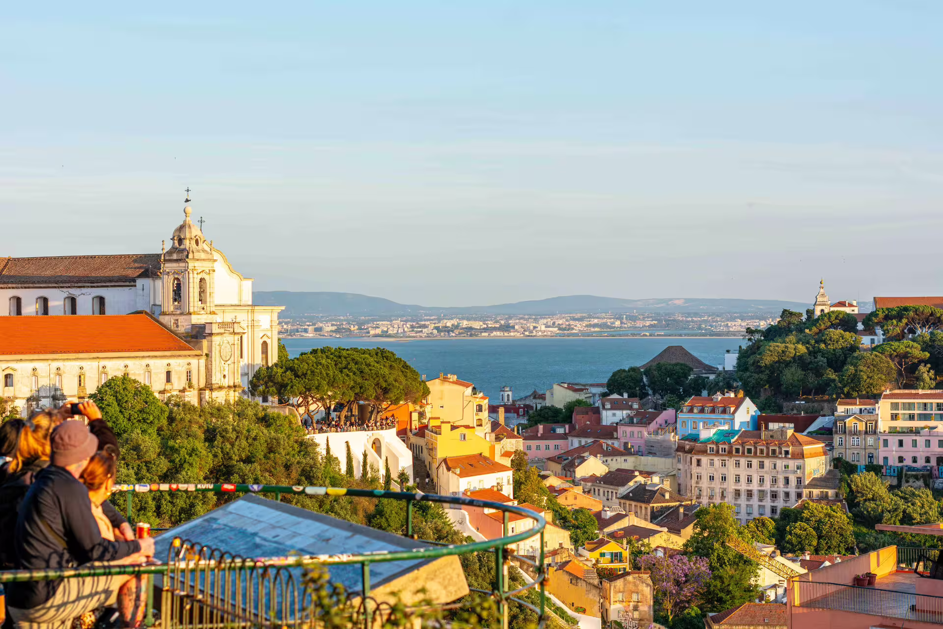 Scenic view of Lisbon's historic architecture and river backdrop at sunset, ideal for a private Christmas lights photo walk.
