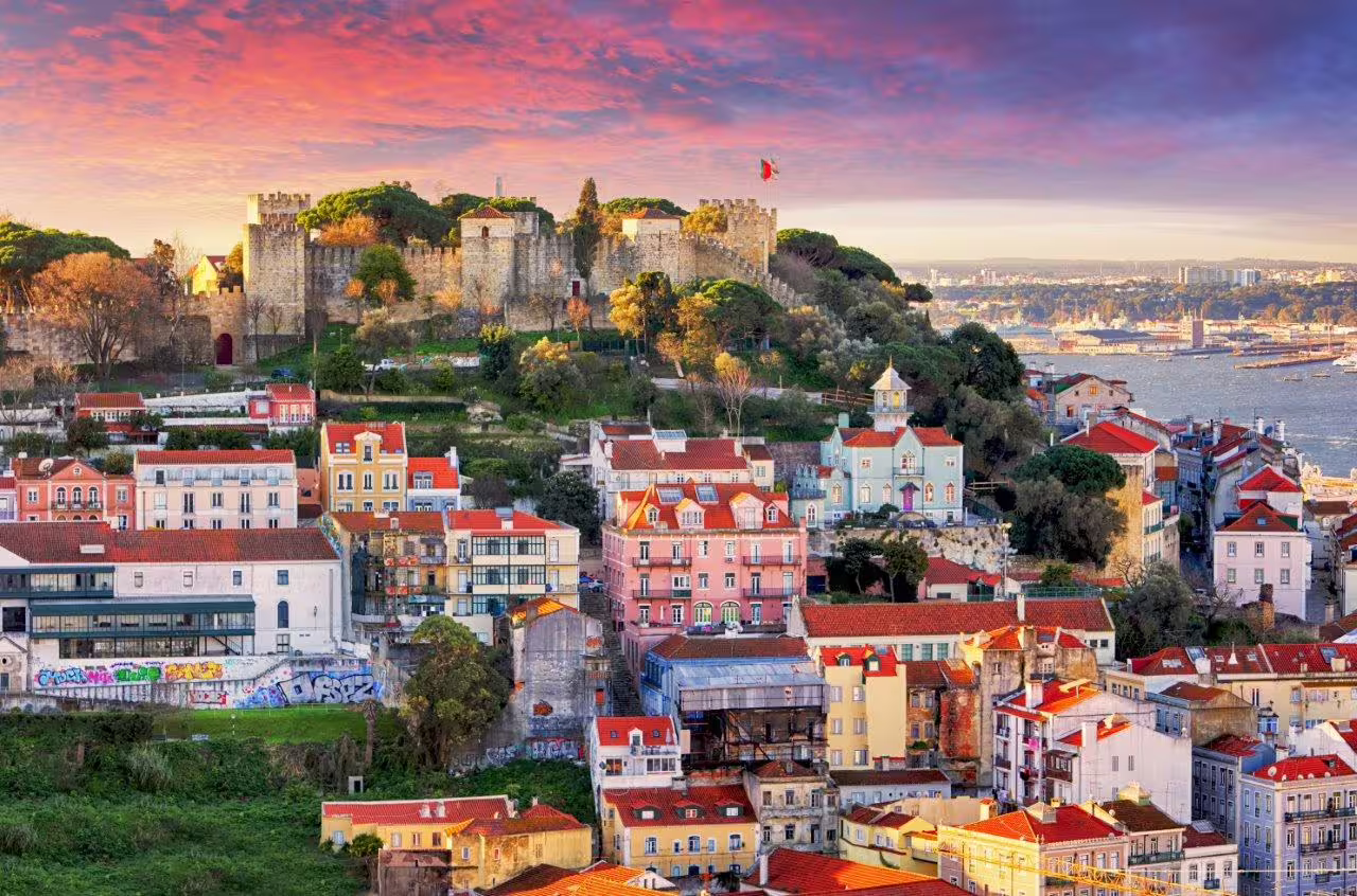 Vibrant sunset over Lisbon's colorful rooftops and historic São Jorge Castle, showcasing Portugal's rich cultural heritage.