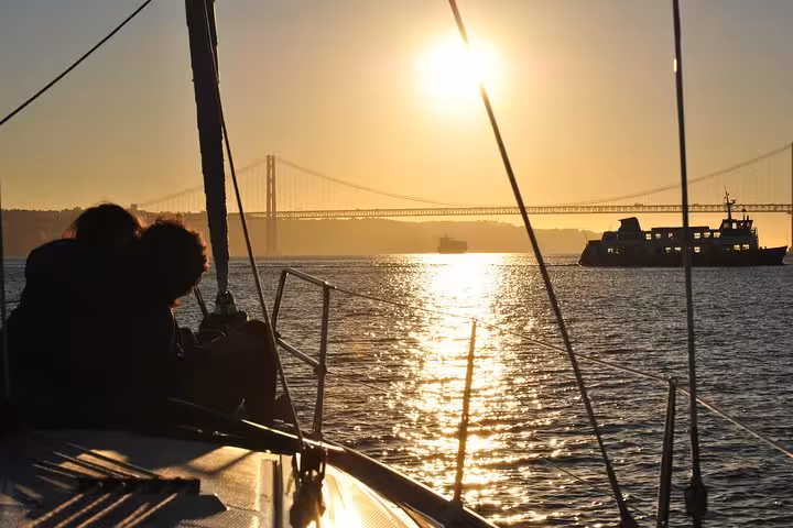 Silhouetted couple on private Lisbon sunset cruise with sparkling wine, Tagus River views and 25 de Abril Bridge