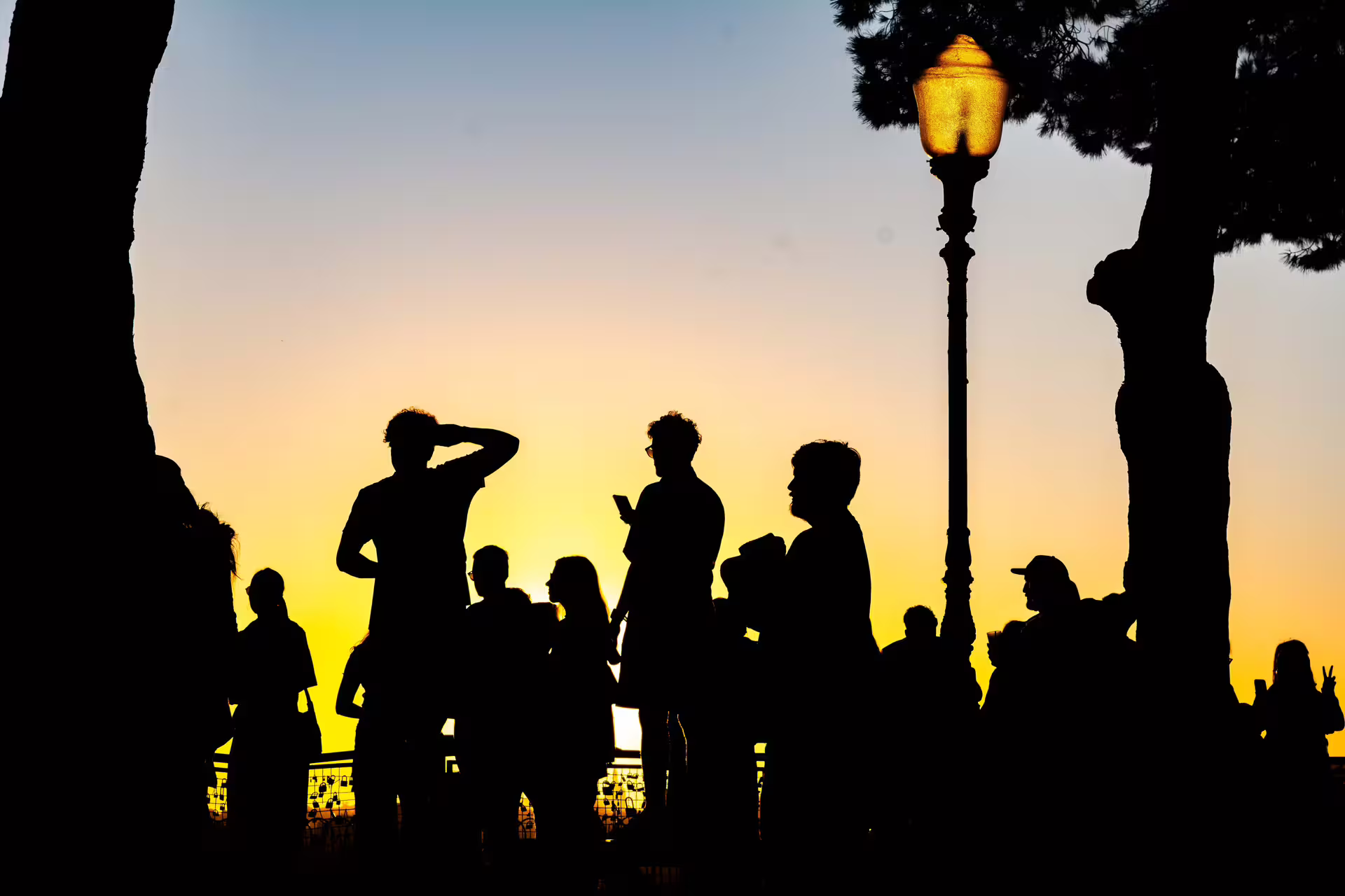 Silhouetted group enjoys Lisbon sunset during a private photo walk, capturing vibrant twilight hues and cityscape views.