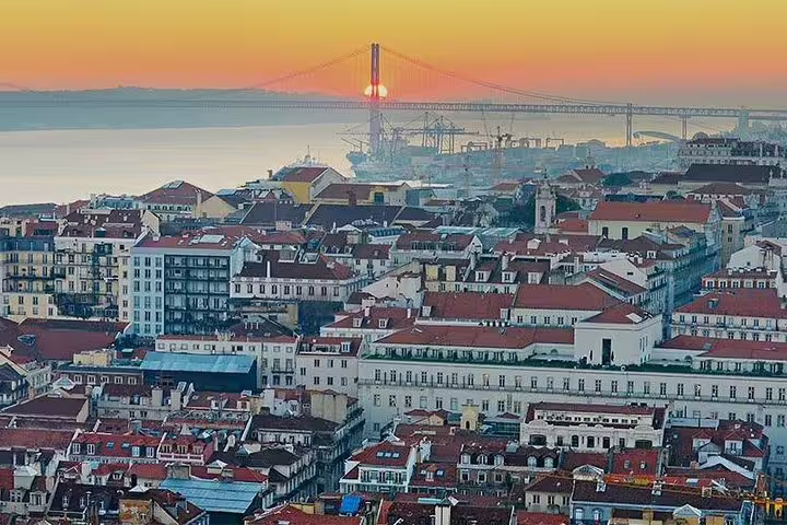 Sunset view over Lisbon rooftops with the iconic 25 de Abril Bridge, perfect for private tour experiences in Portugal's capital.