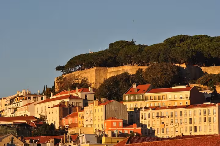Sunlit Alfama and São Jorge Castle hillside viewed from the Tagus on a Lisbon small-group sunset sailing cruise