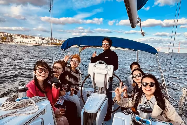 Group enjoying Lisbon sunset sailing on the Tagus River with drinks, part of tuk-tuk and boat tour combo