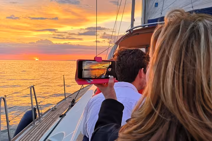 Guest filming Lisbon sunset from a luxury sailing yacht on the Tagus River, scenic evening cruise with 2 drinks