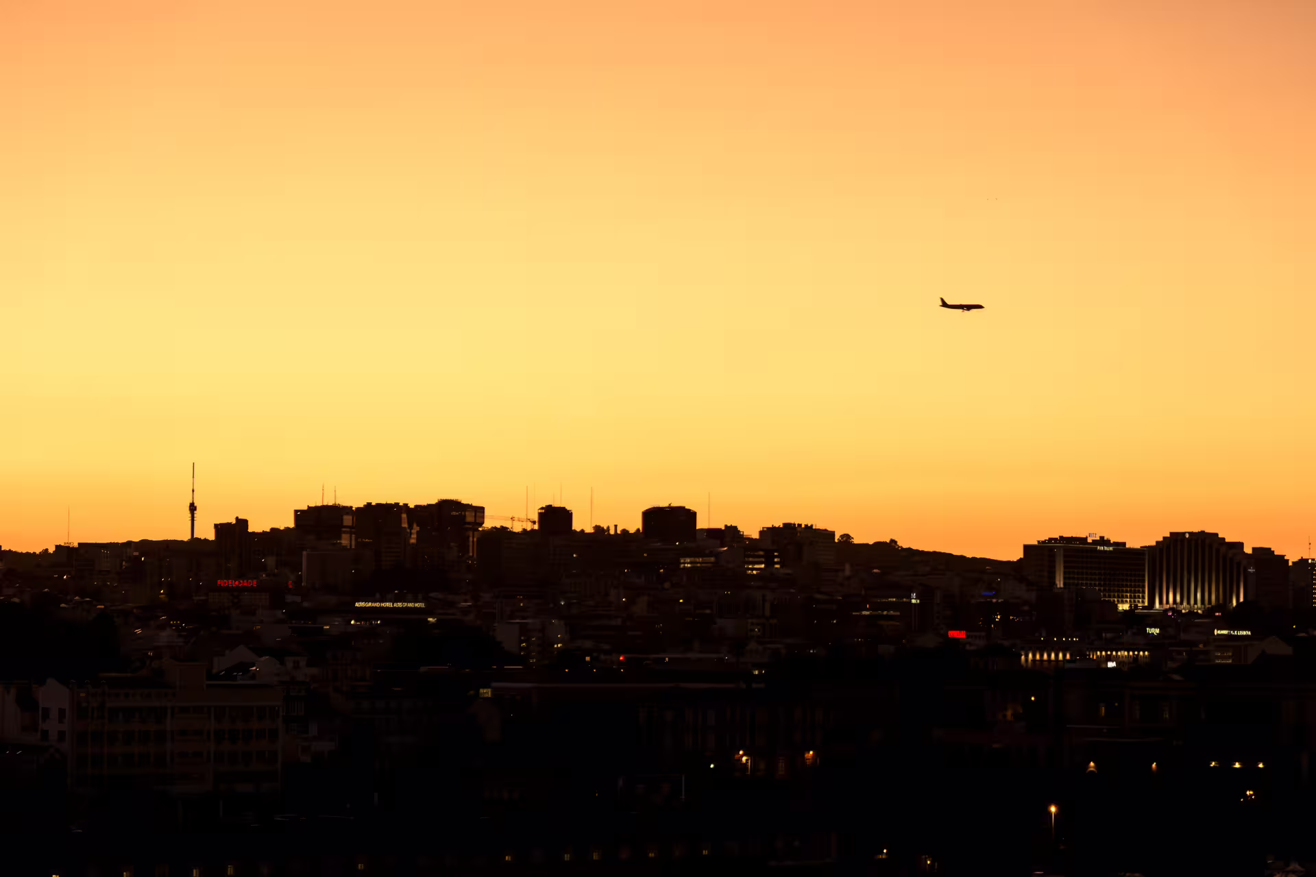 Golden sunset over Lisbon skyline with airplane silhouetted in the sky, perfect for a private sunset and night photo walk.