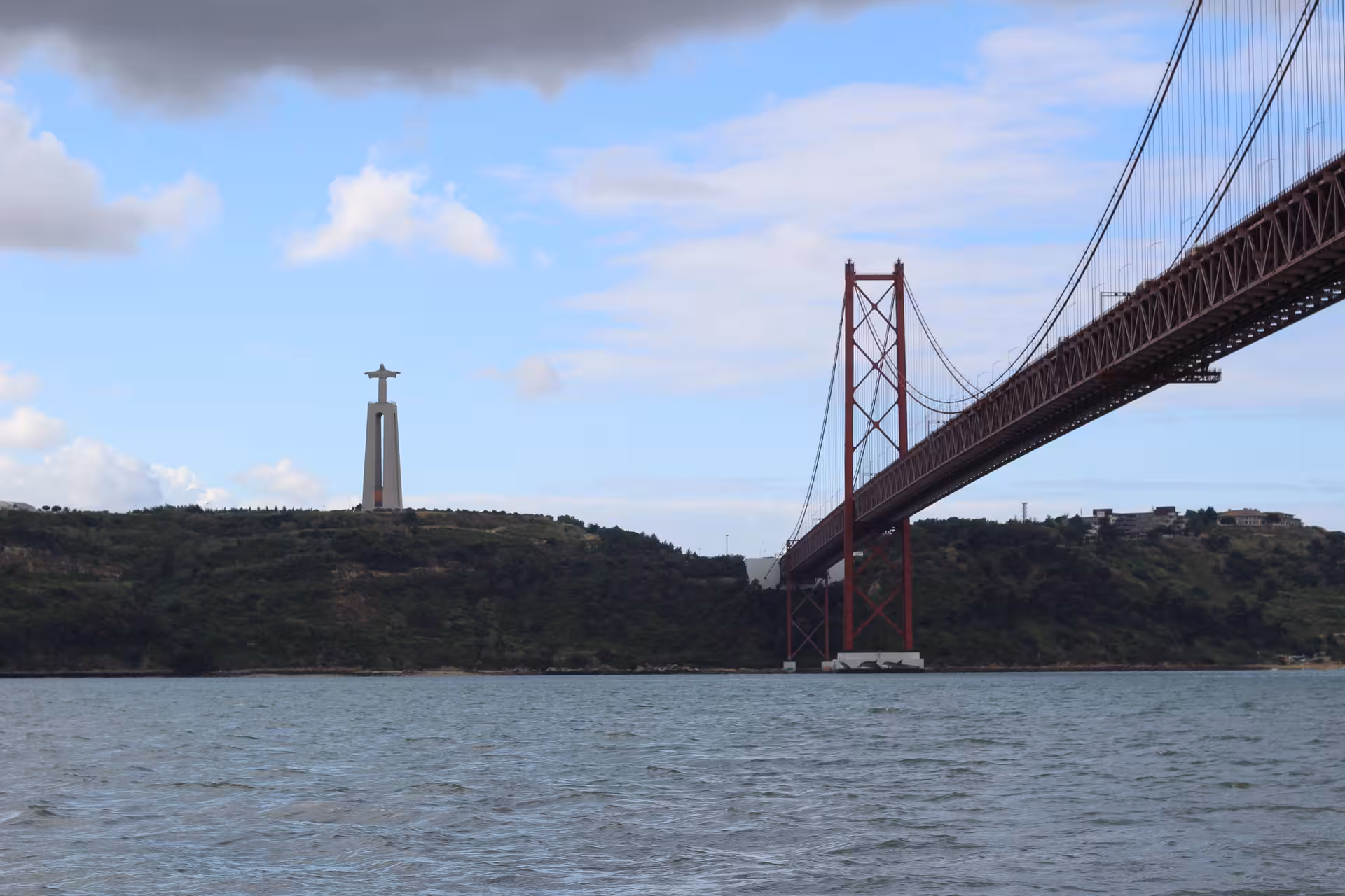 Lisbon sunset speedboat tour view of 25 de Abril Bridge and Cristo Rei over the Tagus River