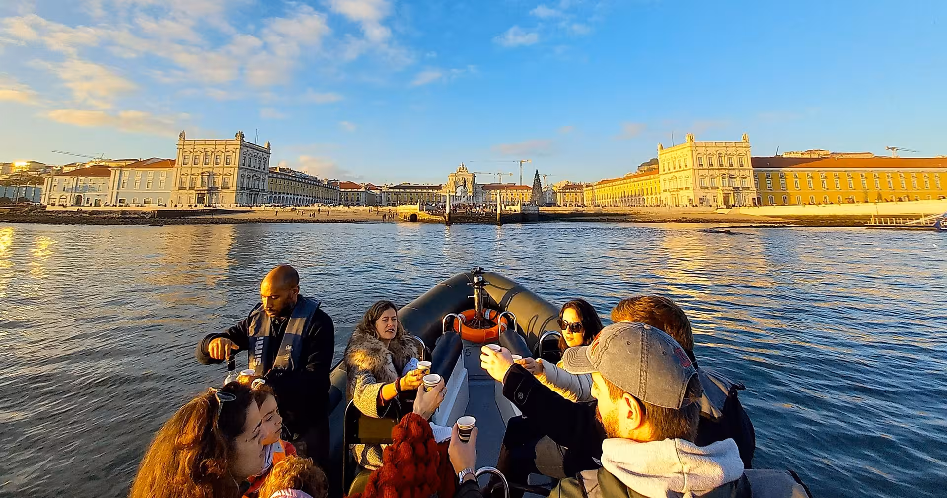 Guests toast on a Lisbon sunset speedboat tour on the Tagus River with Praça do Comércio waterfront views