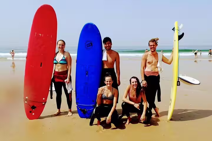 Group of surfers enjoying a sunny day with colorful surfboards on a Lisbon beach, perfect for a surf experience adventure.