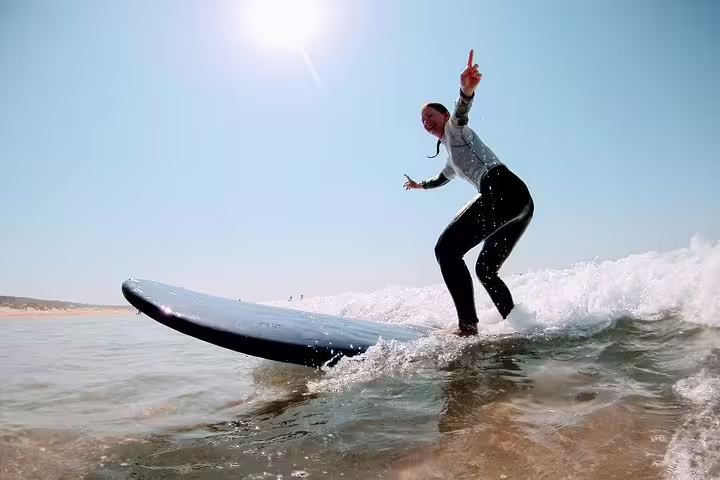 Surfer rides a wave under the sunny Lisbon sky, showcasing the excitement of the Lisbon Surf Experience for adventure seekers.